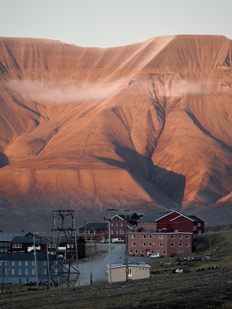 In Longyearbyen fallen die bunten Häuser sofort ins Auge. Die Häuser stehen auf Stelzen, weil der Permafrostboden hier es unmöglich macht, tief zu bauen – eine praktische Lösung, die zugleich das Erscheinungs-bild der Siedlung prägt.